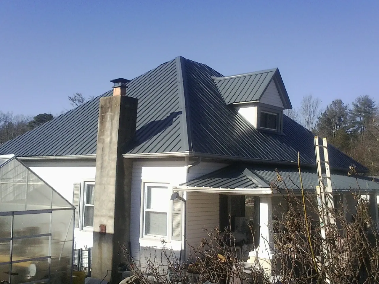 Dark blue standing seam metal roof on a white farmhouse with dormer — Slate & Tile Roof Repair by Roofing Brothers in Telford