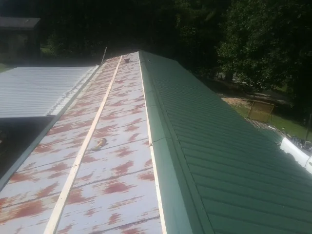Old rusted panels beside newly installed green metal roofing — Wind Damage Roof Repair by Roofing Brothers in Telford