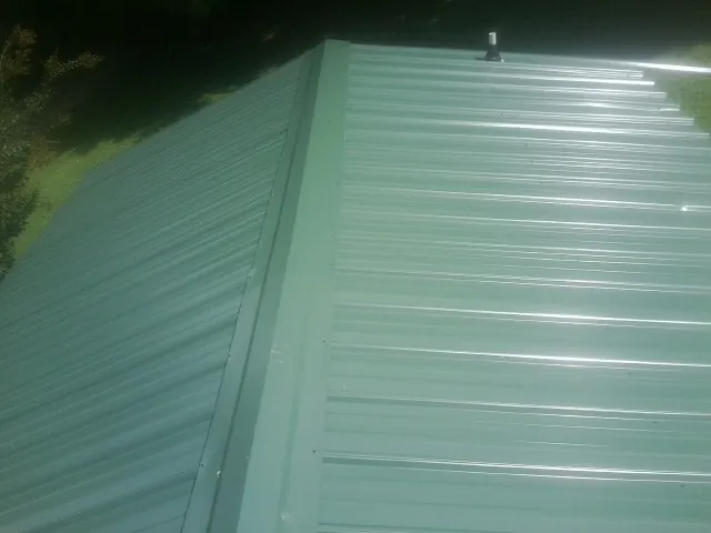 New green metal panels meeting at the ridge of a roof — Flat Roof Repair work by our crew in Telford