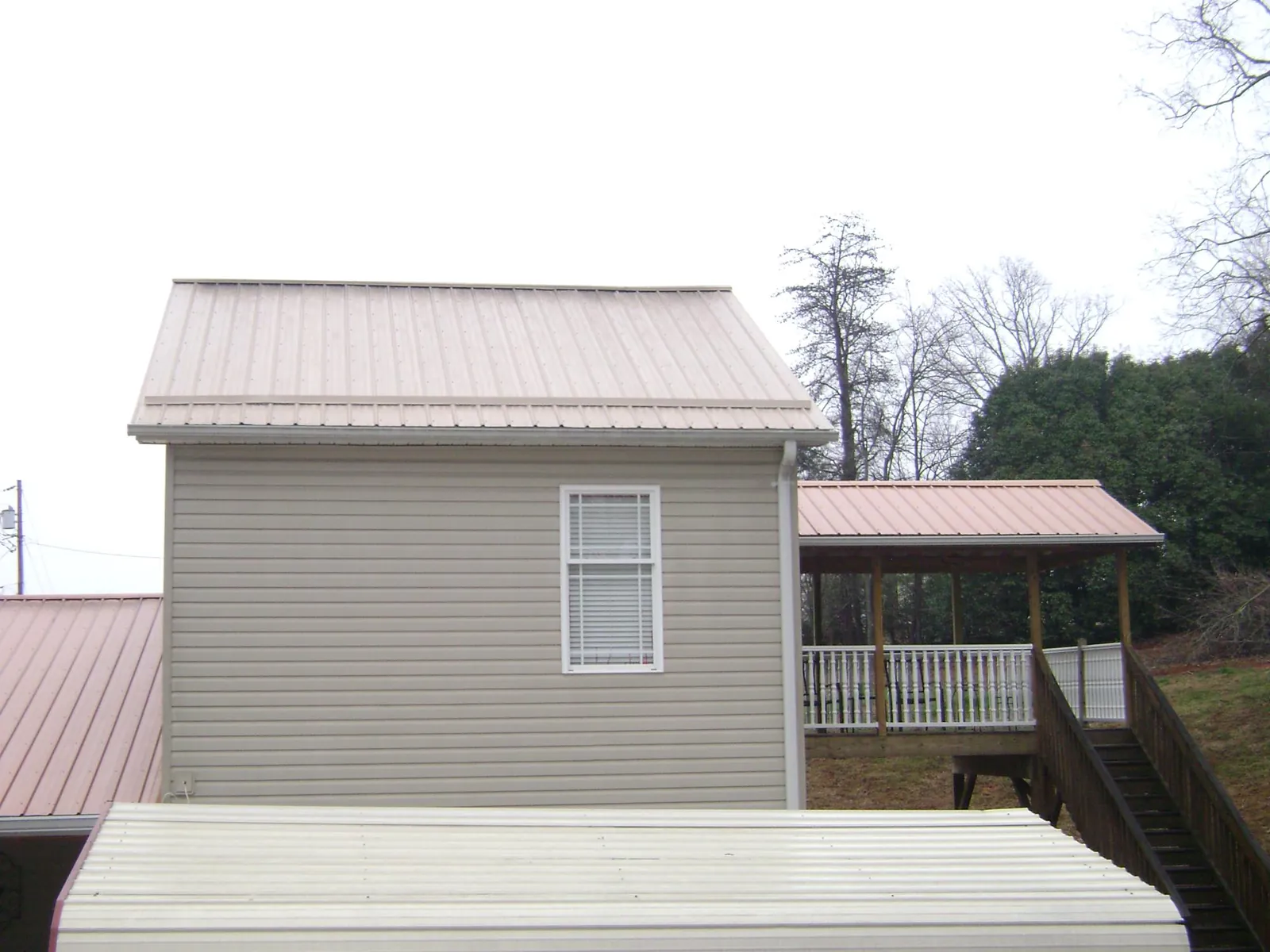 Tan metal roofs on a two story addition and attached porch, from a Roof Replacement job in Telford